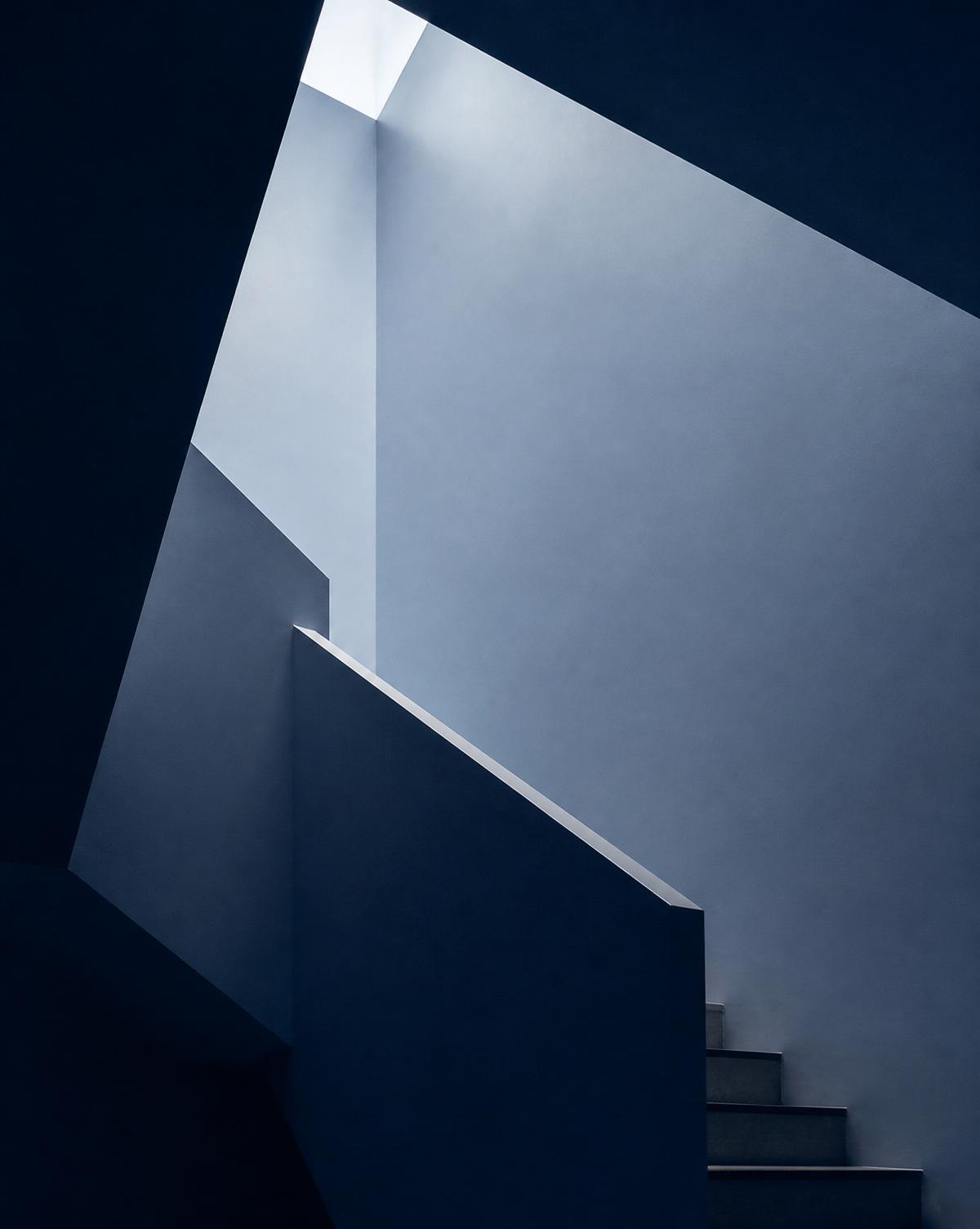 Minimal navy stairwell geometry lit from above